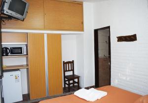 诺诺Los Sauces Posada的小房间设有床、椅子和微波炉