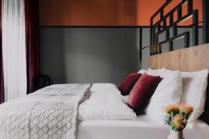 维也纳WELTWIEN Luxury Art Apartments的卧室配有带红色枕头的白色床