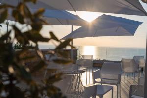 皮佐Villa Rocca - Rooms&SPA的一个带椅子和遮阳伞的庭院和大海