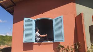 瓜拉雷马Sitio Aconchego Verde Guararema的坐在房子窗户上的人