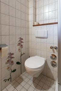 柯尼希斯湖畔舍瑙Waldhauser Hof的浴室配有卫生间,墙上挂有鲜花