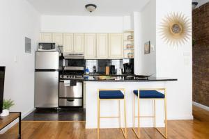 纽约26-3B 1BR prime gramercy WD in unit Courtyard的厨房配有白色橱柜和带2个蓝色吧台凳的台面