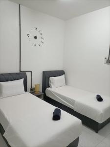 Kampong BembanI-STAY 01 JK Roomstay的墙上挂钟的房间里设有两张床