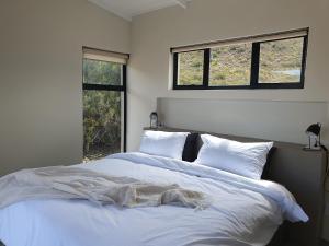 蒙塔古Exhale Cottage的卧室配有一张白色大床和两个窗户