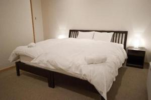 二世古红宝石小木屋的卧室配有一张带白色床单和枕头的大床。
