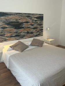 佩斯卡拉Civico 28的一张带两个枕头的床和墙上的绘画