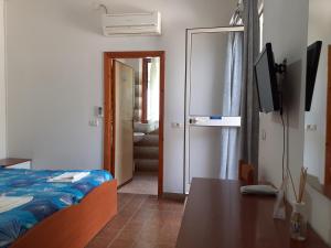 阿祖罗港Albergo Bel Tramonto的一间卧室配有一张床、一张桌子和一台电视