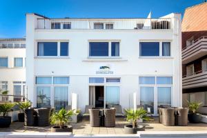 黑尔戈兰岛Hotel auf den Hummerklippen的一座白色的建筑,前面有棕榈树
