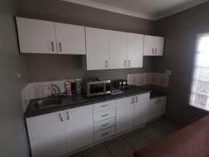 马盖特Aloe Cottage - Ramsgate Ramble Rest的厨房配有白色橱柜、水槽和微波炉