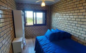 托雷斯Residencial Itapeva的一间卧室设有蓝色的床和砖墙