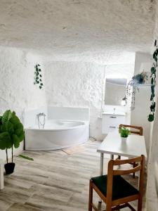 帕特纳Apartamentos La Cueva的白色的浴室设有浴缸和桌子。