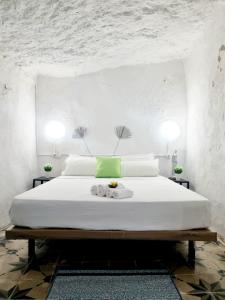 帕特纳Apartamentos La Cueva的卧室配有一张带两张桌子的大型白色床