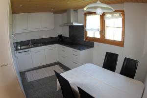 迪森蒂斯Ferienwohnung Rigoleth的厨房配有白色橱柜、桌子和窗户。