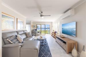 科莱特Sandy Beach House Corlette Unit 1 Waterfront WI-FI Aircon的带沙发和电视的客厅
