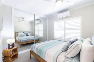 科莱特Sandy Beach House Corlette Unit 1 Waterfront WI-FI Aircon的一间卧室配有一张床和镜子