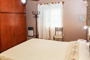 埃利萨镇Lo de Hilda的卧室配有一张白色大床和一把椅子
