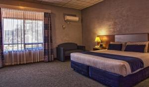 库伯佩迪沙漠卡文酒店的酒店客房带一张大床和一把椅子