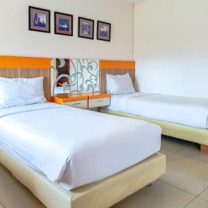 泗水高点服务式公寓酒店的配有白色床单的酒店客房内的两张床