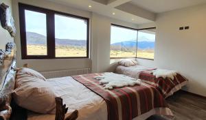 百内三塔Morrena Lodge的一间带两张床的卧室和山景窗户