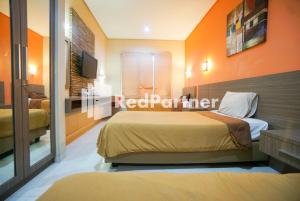 卡拉瓦奇Tirta Mansion Lippo Karawaci Mitra RedDoorz的一间带两张床的卧室,拥有橙色的墙壁