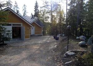 LöparöVilla Linnunlaulu的一座黄色的房子,树林里有一个车库