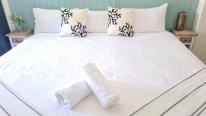 扬巴The Carmel Yamba的一张带白色床单的床和两张毛巾