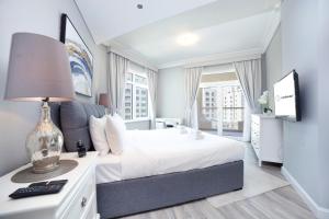迪拜Lux Living on Palm Jumeirah With Beach Access & Complimentary Golf的卧室配有白色的床和带台灯的书桌