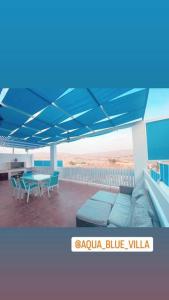 安曼Aqua Blue Villa-Dead Sea, Jordan的露台配有蓝色遮阳伞和桌椅