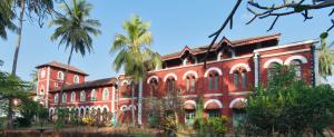 SawantwadiSawantwadi Palace Boutique Art Hotel的一座红砖建筑,前面有棕榈树