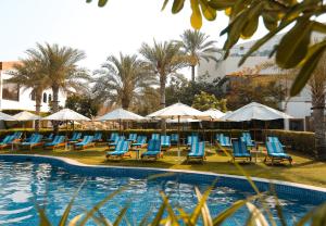 迪拜迪拜海滩Spa度假酒店的一组椅子和遮阳伞,位于游泳池旁