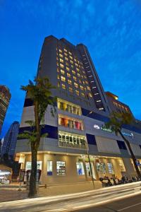 吉隆坡Metrostar Hotel Kuala Lumpur的一座高大的建筑,前面有一棵棕榈树