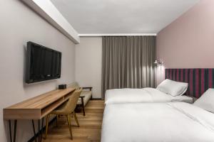 恒春古城河堤垦丁渡假酒店的酒店客房设有两张床、一张桌子和一台电视。