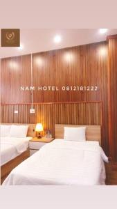 Bản CoKhach san Nam Hotel的酒店客房设有两张床,墙上有标志