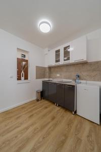 贝尔格莱德M Apartments的一间空厨房,配有白色的橱柜和木地板