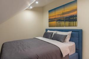 贝尔格莱德Apart Hotel Maksimum的卧室配有蓝色的床和墙上的绘画作品