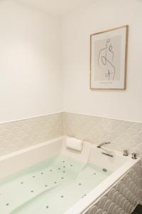 佩兹纳斯Maison 1634 - Centre historique, parking, petit-dejeuner compris, climatisation, piscine的墙上挂着一幅画的房间里设有一个浴缸