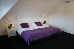 东弗利兰德贺万弗利兰酒店的一间卧室配有一张带紫色床单的大床