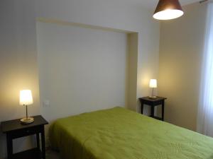 勒帕莱Appartement Le Palais, 2 pièces, 3 personnes - FR-1-418-95的一间卧室配有一张绿色的床和两张台灯。