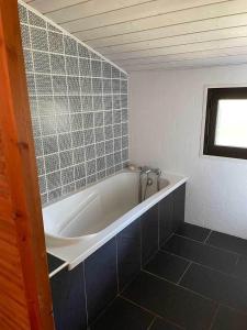卡普费雷Yamina Lodge的带浴缸的浴室和瓷砖墙