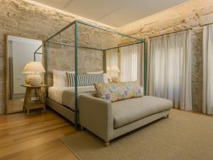 波尔图Saboaria Boutique Hotel Porto的一间卧室配有天蓬床和沙发