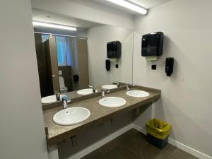 扎鲁亚斯Zarautz Surf House的一间带三个水槽和大镜子的浴室