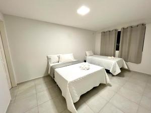 嘎林海斯港Casa em Porto de Galinhas by AFT的一间卧室配有两张带白色床单的床。