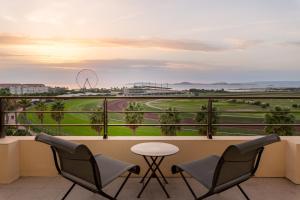 马赛金色郁金香马西利亚别墅酒店的一个带桌椅的阳台和一个高尔夫球场