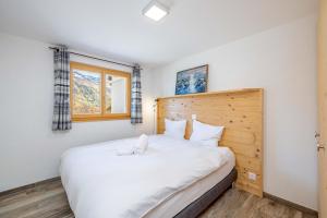 RiddesChalet Amerhone - Luxury chalet With Jacuzzi的卧室配有一张白色大床和木制床头板