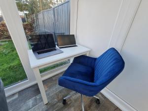 HornchurchElm Park Cheerful 4-Bedroom Holiday Home的一张带笔记本电脑和蓝椅的书桌