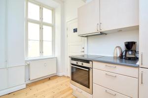 哥本哈根Scandinavian Style 3BR in Copenhagen City Centre的厨房配有白色橱柜和炉灶烤箱。