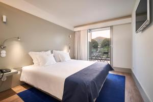 阿尔库什迪瓦尔德维什Ribeira Collection Hotel by Piamonte Hotels的酒店客房设有一张大床和一个阳台。