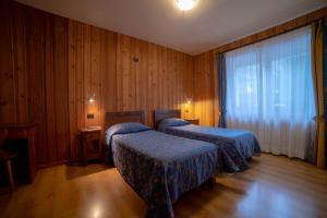 尚波吕克Family Apartments Le Chalet的配有木墙和木地板的客房中的两张床
