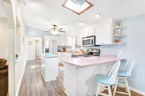 泰比岛Tybee Southern Comfort的厨房配有白色橱柜和蓝色凳子