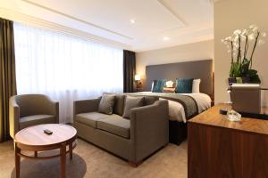 伦敦Thistle London Marble Arch的酒店客房配有床、沙发和桌子。